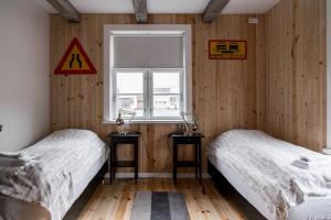 Ce lit se trouve dans un dortoir doté de murs en bois et d'une fenêtre. dans l'établissement Tangs, à Ísafjörður