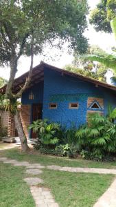 una casa azul con un árbol delante en Hóspedes da Terra Pousada & Chalés, en Arraial d'Ajuda