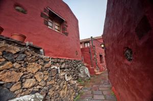 un edificio rosso con un muro in pietra e una finestra di Poblado Jirdana I a La Torre