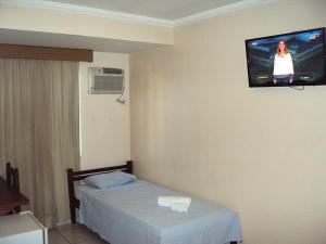 a room with a bed and a tv on the wall at Hotel Paineiras in Itumbiara