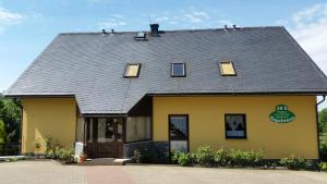 a yellow building with a gray roof at Pension Gerlach in Seiffen