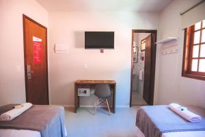 a room with two beds and a desk and a television at CLH Suites Ilha Grande in Abraão