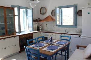eine Küche mit einem Holztisch und blauen Stühlen in der Unterkunft 360 Blue in Fira