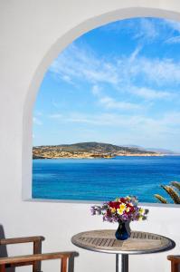 a table with a vase of flowers on a table with a window at Christina's House in Koufonisia