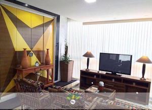 a living room with a flat screen tv and a couch at Hotel Garden - Norte in Santa Maria