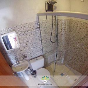 Un baño con ducha, inodoro y lavabo. en Hotel Garden, en Santa Maria