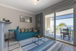 a living room with a blue couch and a balcony at Le Petrel Blanc - Appartement sur la plage de la Souris Blanche in Trois Bassins