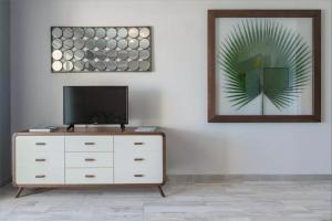 a living room with a tv and a white dresser at Le Petrel Blanc - Appartement sur la plage de la Souris Blanche in Trois Bassins