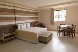 a bedroom with a bed and a table and chairs at Vale dos Carajás Hotel in Parauapebas