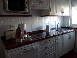 une cuisine avec des placards blancs et un comptoir dans l'établissement Casa Rural Costanilla, à San Miguel de Valero