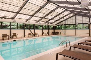 a swimming pool with tables and chairs in a building at Hyatt Place Baltimore Owings Mills in Owings Mills
