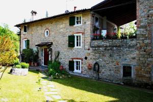a large stone house with a yard in front of it at La Quercia - la maison des arts in Vezzano sul Crostolo