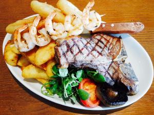 a plate of food with steak and french fries and shrimp at King Alfred Hotel in Barrow in Furness