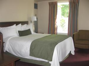 a bedroom with a bed and a chair and a window at Glynmill Inn in Corner Brook