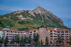 a large building with a mountain in the background at The Grand Lodge Hotel and Suites in Mount Crested Butte