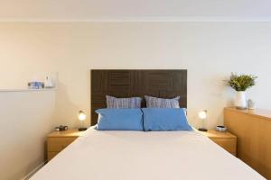 a bedroom with a large bed with blue pillows at Grande Esplanade Studio in Sydney