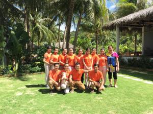 a group of people in orange shirts posing for a picture at Peppercorn Beach Resort in Phú Quốc