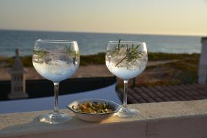 Dois copos de vinho sentados numa saliência com uma taça de comida. em Faro Beach House em Faro