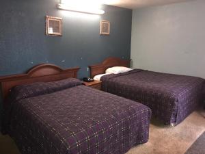 ein Hotelzimmer mit 2 Betten mit lila Bettwäsche in der Unterkunft Flamingo Motel Marshalltown in Marshalltown