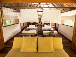 a room with four beds and white curtains at Inkaterra Hacienda Concepcion in Puerto Maldonado