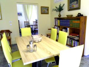 ポルト・ラフティにあるLuxury villa houseのダイニングルームテーブル(黄色い椅子付)、本棚