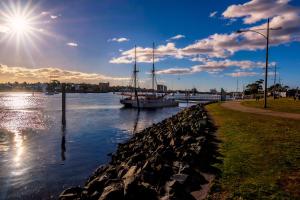 a boat is docked in a river with the sun at Argosy Motor Inn in Devonport