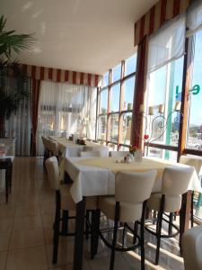 a restaurant with white tables and chairs and windows at Sundance Mountain Resort in Turracher Hohe