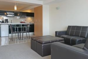 a living room and kitchen with black leather furniture at Capri Reforma 410 in Mexico City