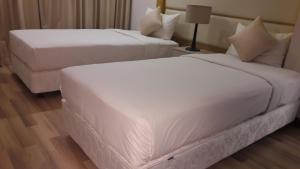 two beds in a hotel room with white sheets at Bluesky Serviced Apartment Airport Plaza in Ho Chi Minh City