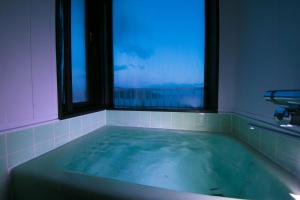 a bath tub with a window in a bathroom at Ofunato Onsen in Ōfunato