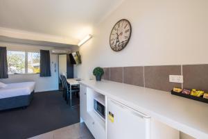 a room with a bed and a clock on the wall at Caboolture Motel in Caboolture