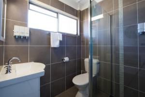 a bathroom with a toilet and a sink and a window at Caboolture Motel in Caboolture