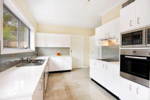 a kitchen with white cabinets and a large window at The Beach Townhouse in Hawks Nest