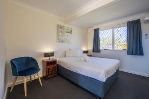 a bedroom with a bed and a chair and a window at Caboolture Motel in Caboolture