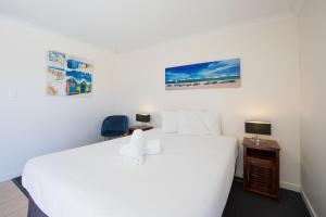 a bedroom with a large white bed and a desk at Caboolture Motel in Caboolture