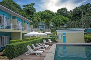 a pool with chairs and umbrellas next to a building at Aqua Beads Samed in Ko Samed