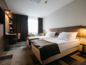 a hotel room with two beds and a desk at Q Hotel Plus Katowice in Katowice