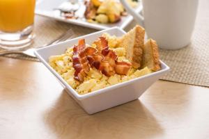 a bowl of food with bacon and toast on a table at Hyatt Place Austin Airport in Austin