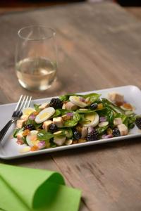 a plate of salad on a table with a glass of wine at Hyatt Place Austin Airport in Austin