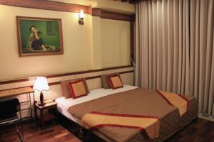 ein Schlafzimmer mit einem Bett und einem Bild einer Frau in der Unterkunft Bi Saigon Hotel in Ho-Chi-Minh-Stadt