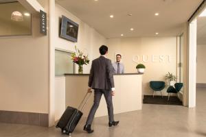 a man with a suitcase walking into a guest room at Quest Whangarei in Whangarei