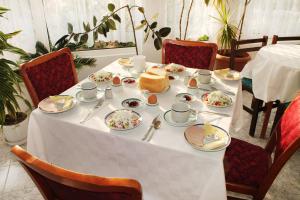 een tafel met een witte tafeldoek en borden met voedsel bij Hotel Bobchev in Sozopol