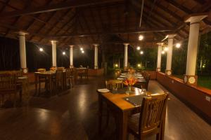 ein Restaurant mit Holztischen und -stühlen in der Nacht in der Unterkunft Palmgrove Lake Resort in Alappuzha