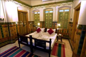 Schlafzimmer mit einem Bett mit grünen Türen und roten Kissen in der Unterkunft Chettinadu Mansion – An Authentic Heritage Palace in Kānādukāttān