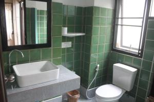 W wyłożonej zielonymi kafelkami łazience znajduje się umywalka i toaleta. w obiekcie Baan Warabordee w mieście Chiang Rai