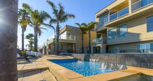 una piscina frente a una casa con palmeras en The Bluff Resort Apartments en Encounter Bay
