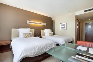 a hotel room with two beds and a glass table at Pullman Sydney Olympic Park in Sydney