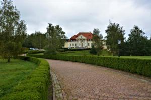 una strada di mattoni che conduce a una grande casa bianca di Dwor Osieczek a Pniewy