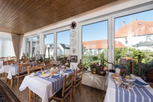 ein Restaurant mit Tischen und Stühlen und großen Fenstern in der Unterkunft Atlantic Hotel Garni in Wangerooge