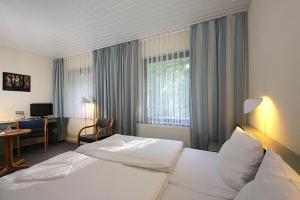 Habitación de hotel con cama blanca y escritorio en Gastehaus Chorin en Chorin